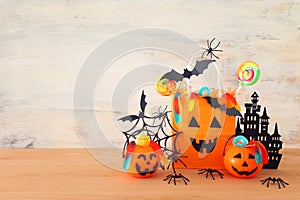 Holidays image of Halloween. Pumpkins, bats, treats, paper gift bag over wooden table