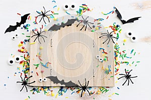 holidays image of Halloween. spiders, bats and wooden board frame for text or mock up over white table