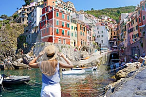 Holidays in Italy. Beautiful woman looking the picturesque village overhanging cliffs Riomaggiore, Cinque Terre, Italy