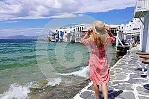 Holidays in Mykonos. Rear view of young woman walking on Little Venice neighborhood in Mykonos Island, Greece