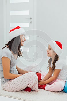 Holidays, presents, christmas, x-mas concept - happy mother and child girl in santa helper hats with gift box