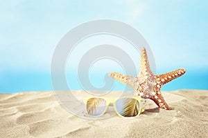 Holidays. sand beach, sunglasses and starfish in front of summer sea background with copy space