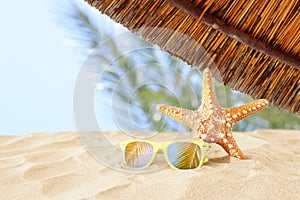 Holidays. sand beach, sunglasses and starfish in front of summer sea background with copy space