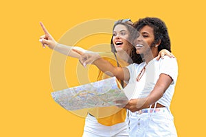 Holidays and tourism concept - beautiful girls looking for direction on yellow background.