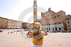 Holidays in Tuscany. Back view of beautiful woman visiting main square in Siena city, Tuscany, Italy