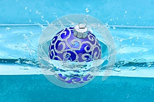 Holidays and vacation concept. Festive decoration for Christmas tree, blue ball dropped into water with splashes, blue
