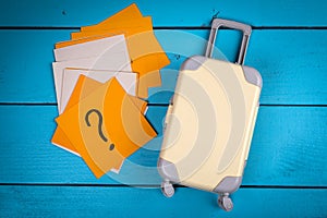 Holidays, vacations and travel planning concept. Sticky notes and suitcase on a wooden background
