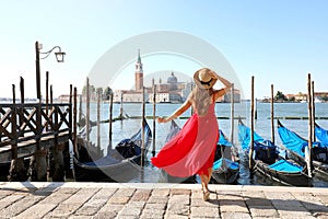 Holidays in Venice. Back view of beautiful girl in red dress enjoying view of Venice Lagoon with the island of San Giorgio