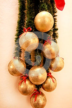 Holidays wreath of fir branches with Christmas baubles. Twigs pine, golden balls and red bows as Christmas decorations on wall.