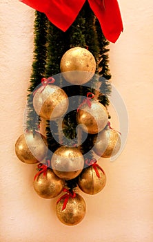 Holidays wreath of fir branches with Christmas baubles. Twigs pine, golden balls and red bows as Christmas decorations on wall.