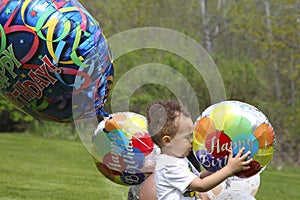 Holing colorful balloon, two-year-old boy celebrates birthday