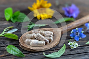 Holistic medicine approach. Healthy food eating, dietary supplements, healing herbs and flowers. wooden background, c. photo