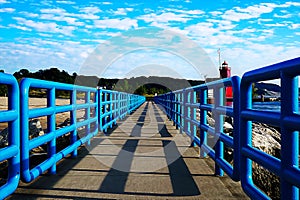 Pier with a bright blue fence in perspective. Big Red Lighthouse on the Lake Michigan. oil paint effect