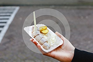 Holland herring fish in female hand outside. Traditional Dutch street food, herring fish. Stock photo street food, herring fish