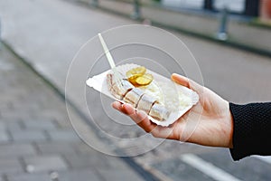 Holland herring fish in female hand outside. Traditional Dutch street food, herring fish. Stock photo street food, herring fish