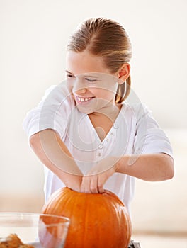 Hollowing out a pumpkin for a jack-o-lantern. A little girl hollowing out a pumpkin in her kitchen for halloween.