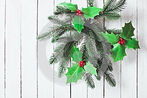 Holly and fir twigs on wood wall