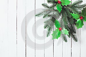 Holly and fir twigs on wood wall