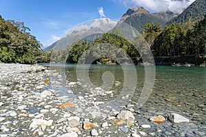 Hollyford River flowing between mountains over flat wide stony riverbed