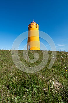 Holmsberg Lighthouse, an orange light house on the Reykjanes Peninsula in Iceland