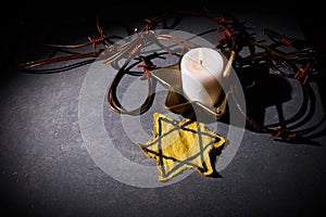 Holocaust memory day. Barbed wire star and burning candle on black background
