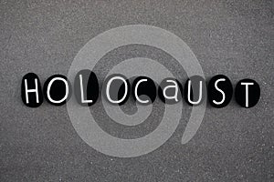 Holocaust word composed with black colored stone letters over black volcanic sand photo