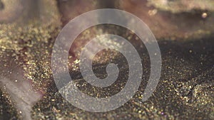 Holographic makeup cosmetics texture macro. Liquid Glitter gold and pink ink mix. Beautiful holiday multicoloured bokeh