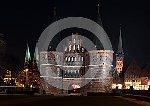 Holstentor and church towers in Luebeck iluminated at night, med photo