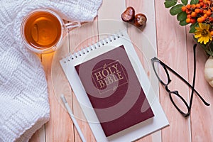 Holy bible and autumn cozy top view on wooden background. Bible study autumn concept