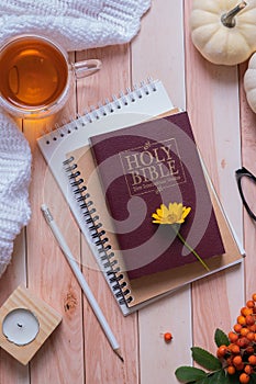 Holy bible and autumn cozy top view on wooden background. Bible study autumn concept
