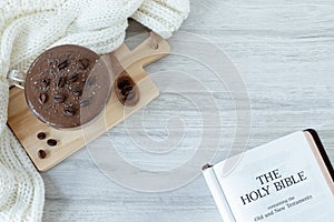 Holy bible book, coffee cup and woolen scarf on table with copy space, top view