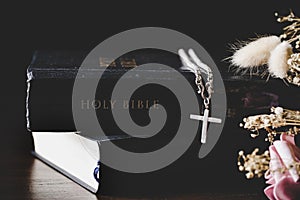 Holy bible book with cross or crucifix on old black wooden background. Christian catholic with protestant pray and study in church