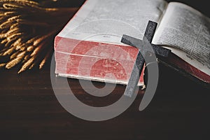 Holy bible book with cross or crucifix on old black wooden background. Christian catholic with protestant pray and study in church