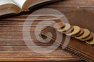 Holy bible book, stack of coin money, and old wallet on wooden table, Christian tithing concept