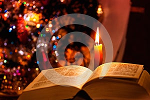 Holy Bible with candle on bokeh