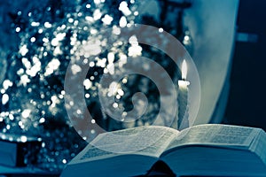 Holy Bible with candle on bokeh