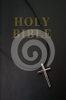 Holy Bible cover and metallic cross on necklace