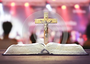 The holy bible and the crucifix over burred concert hall background