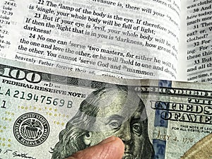 The Holy Bible in English with a tab from the $ 100 banknote showing a passage from the Gospel according to St. Matthew 6:24 photo