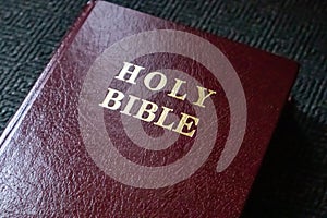 Holy Bible gold text on a leather cover book brown red color, close up view