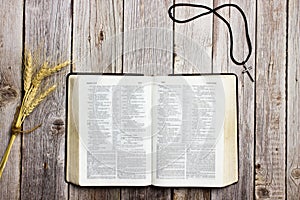 Holy Bible with natural wheat and a cross over the wooden table.