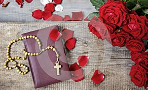 Holy Bible, rosary and red rose petals