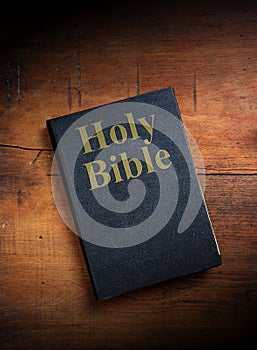 Holy Bible on wooden background. Christians black religious book on vintage brown table