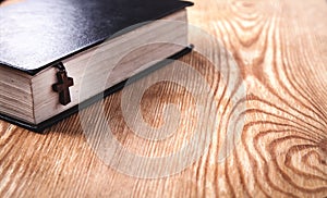 Holy Bible with wooden cross on wooden table