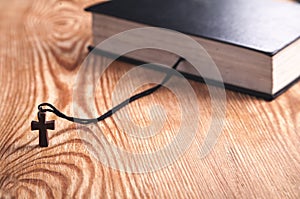 Holy Bible with wooden cross on wooden table