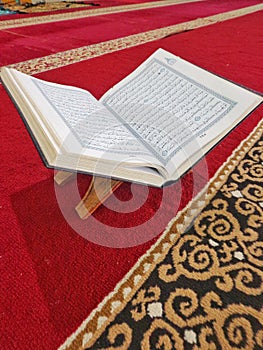 The holy book Al Qur& x27;an isolated on the wood and red carpet of an Indonesian mosque.