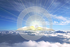 Holy book Bible above the clouds in the rays of bright sacred radiance.