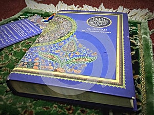 The holy book of the Koran is blue on a prayer mat