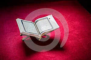 Holy book of Koran on stand on red carpet
