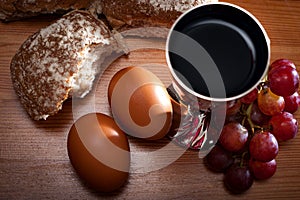 Holy Communion and Easter concept with The Holy Bible. Bread, eggs, grapes and a silver chalice of red wine
